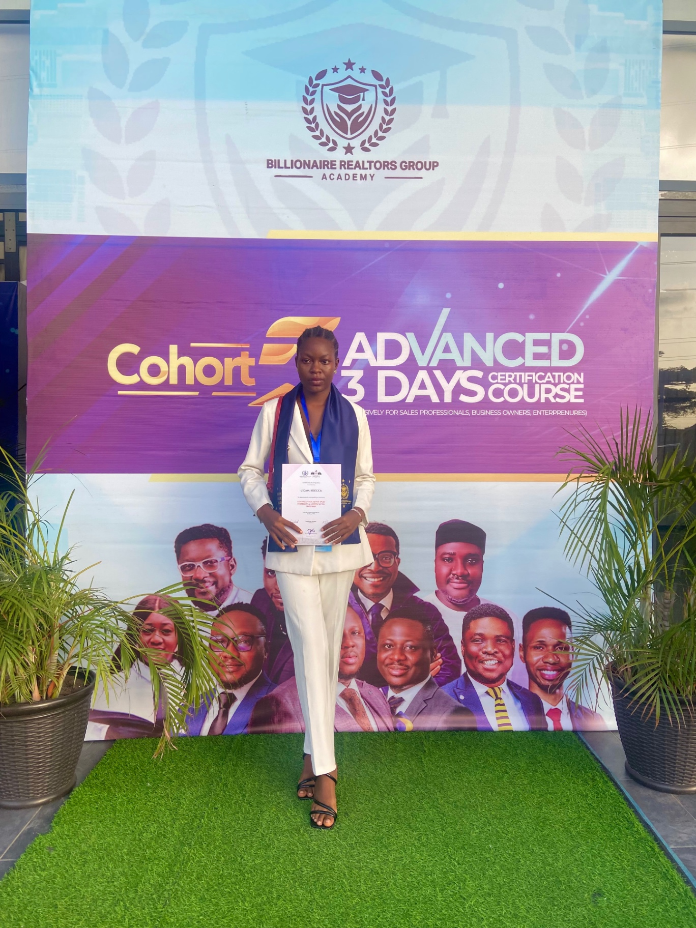 Favour standing with a real estate academy certification banner